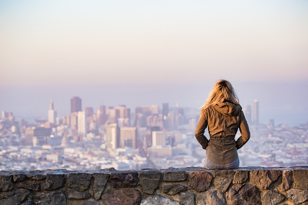 A women sitting on a brick wall enjoying the view of the city